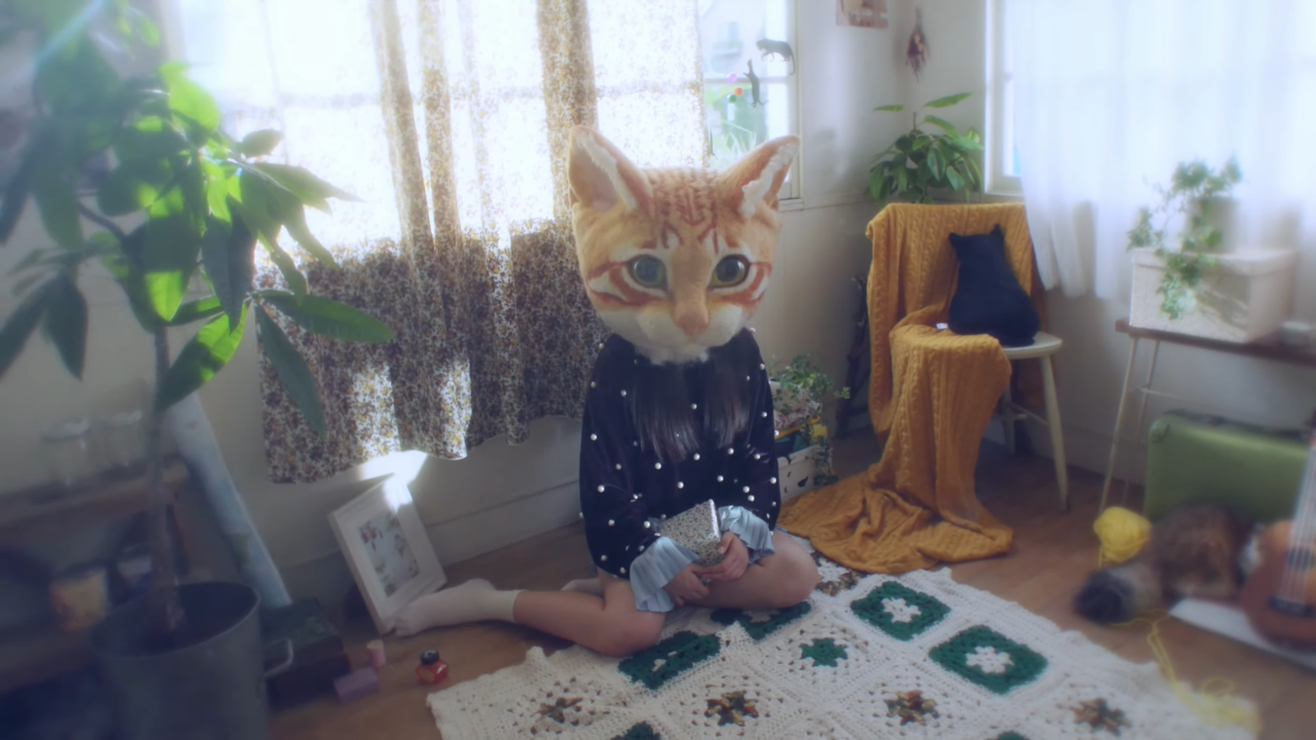 Hyunjin sitting on the floor of her home. She is wearing a large orange cat head.